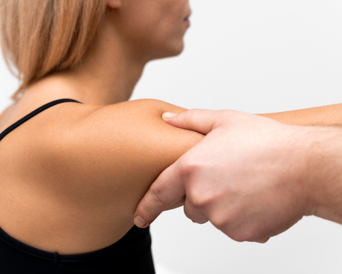 woman having shoulder assessed by physio